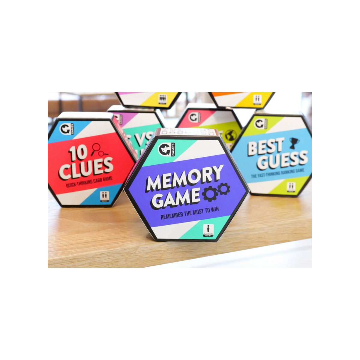 Hexagonal game boxes with colorful designs and text on a wooden surface