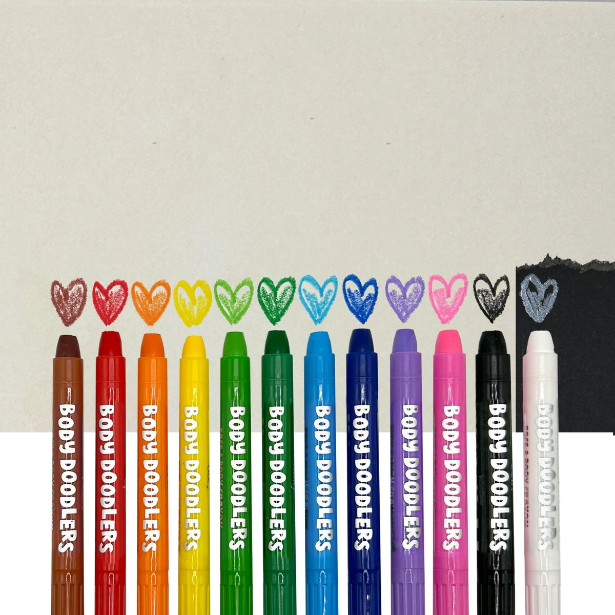 Set of Body Doodlers markers in various colors with heart shapes made from black marker on a light gray background.
