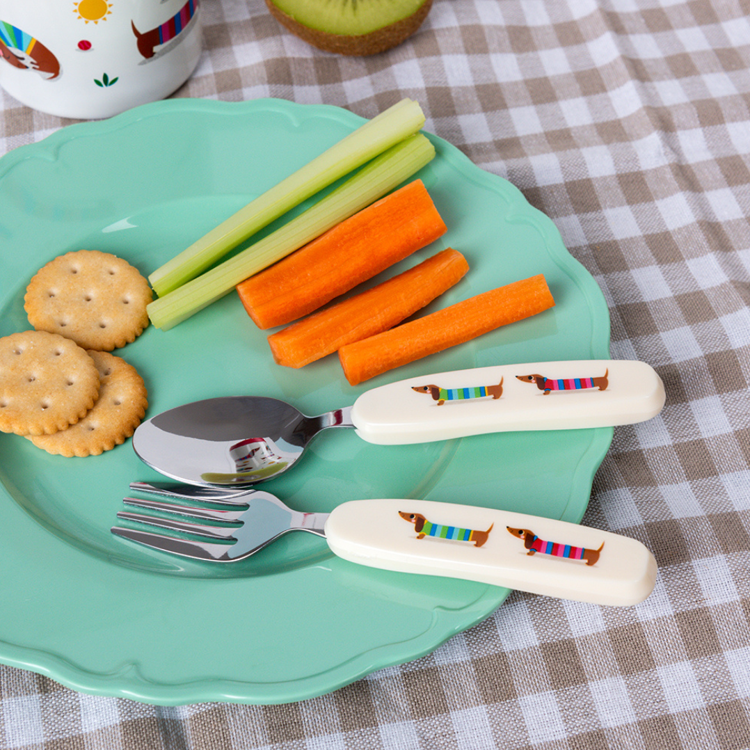 Children's plate with crackers, carrots, celery, and cutlery on a checkered tablecloth.