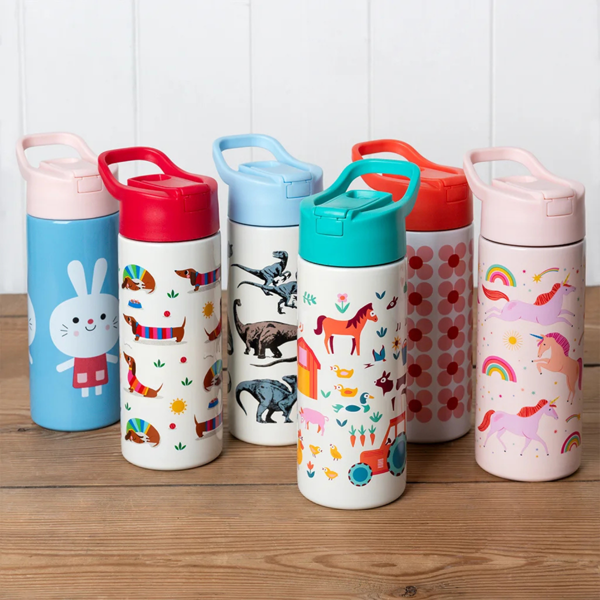 Set of colorful water bottles with animal and nature-themed designs on a wooden surface.
