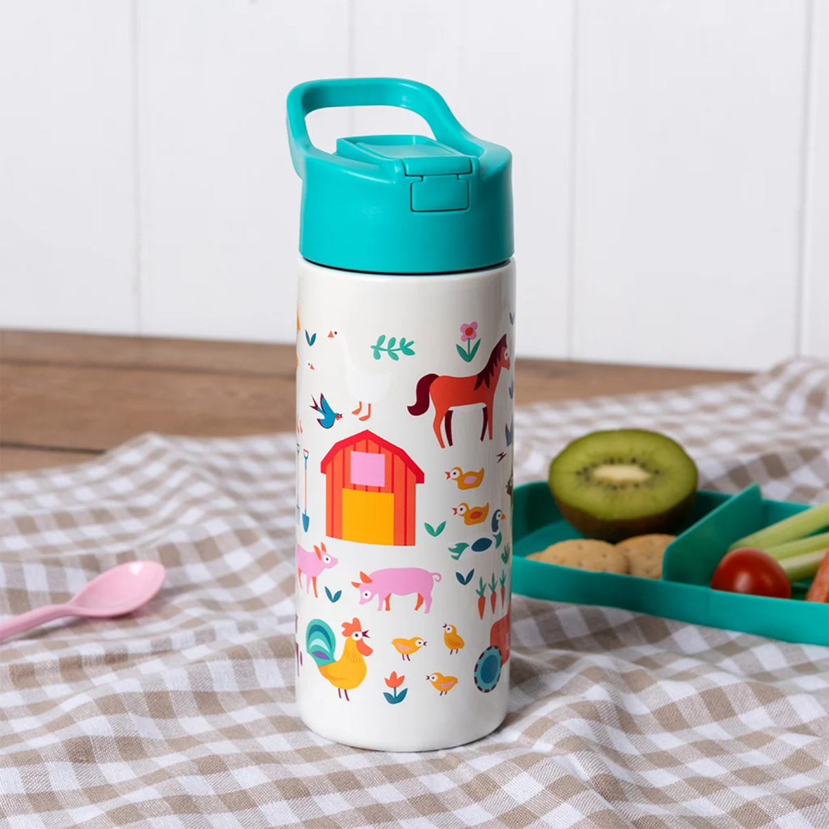 Children&#39;s water bottle with farm animal design on a checkered tablecloth
