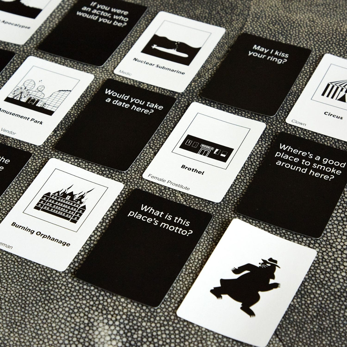 A selection of game cards fanned out face-up, showing clear, readable text prompts designed to spark deceptive social maneuvering.
