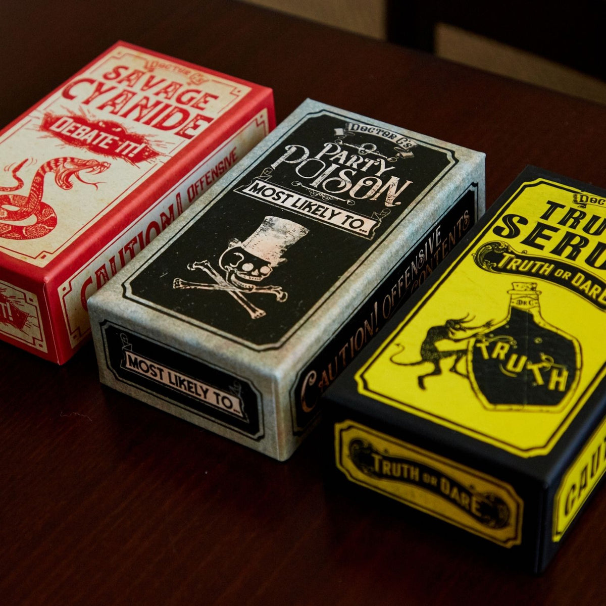 Three playing card decks with themed boxes on a wooden surface
