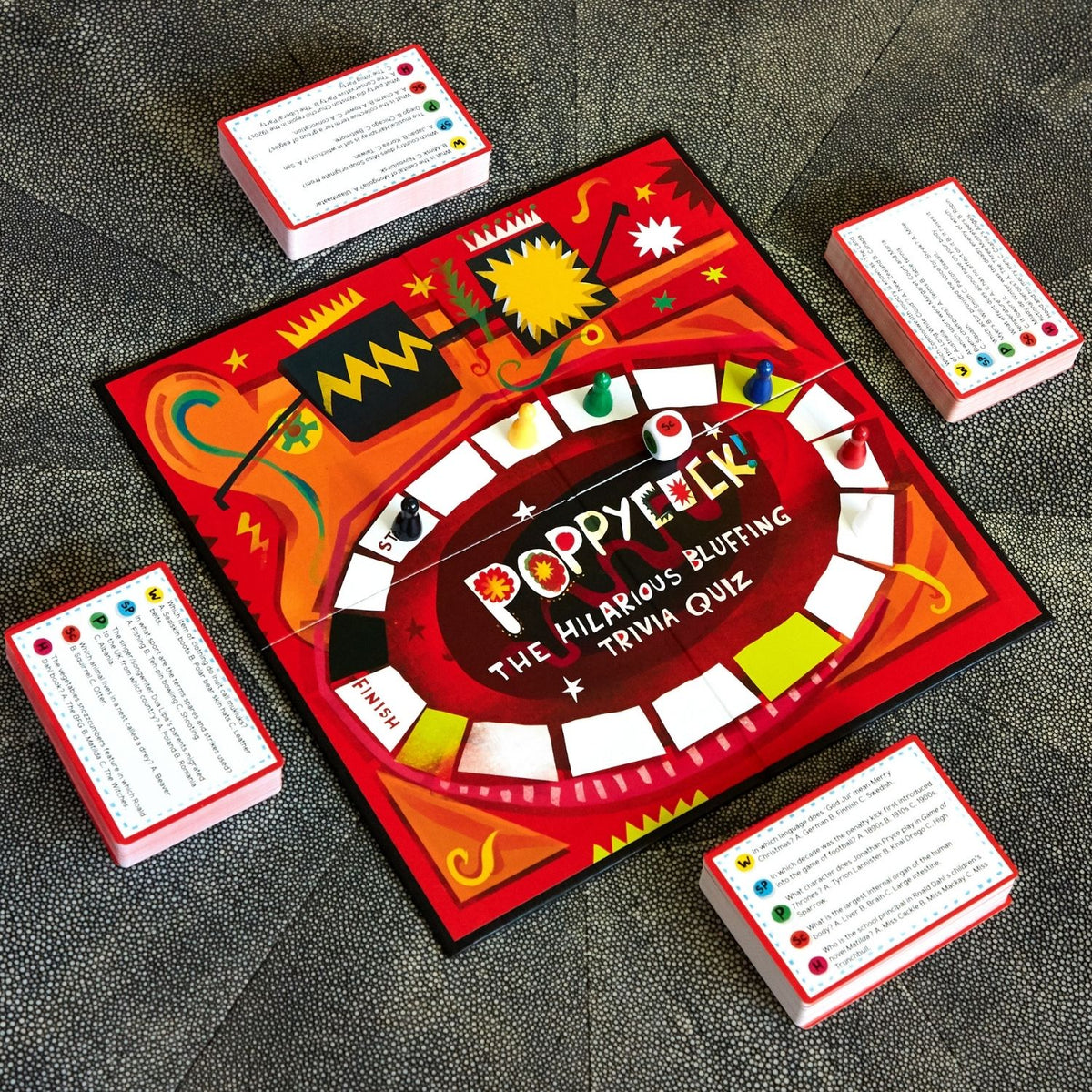 The contents of the game box neatly arranged, displaying the trivia cards, scorepad, instruction manual, and player tokens.
