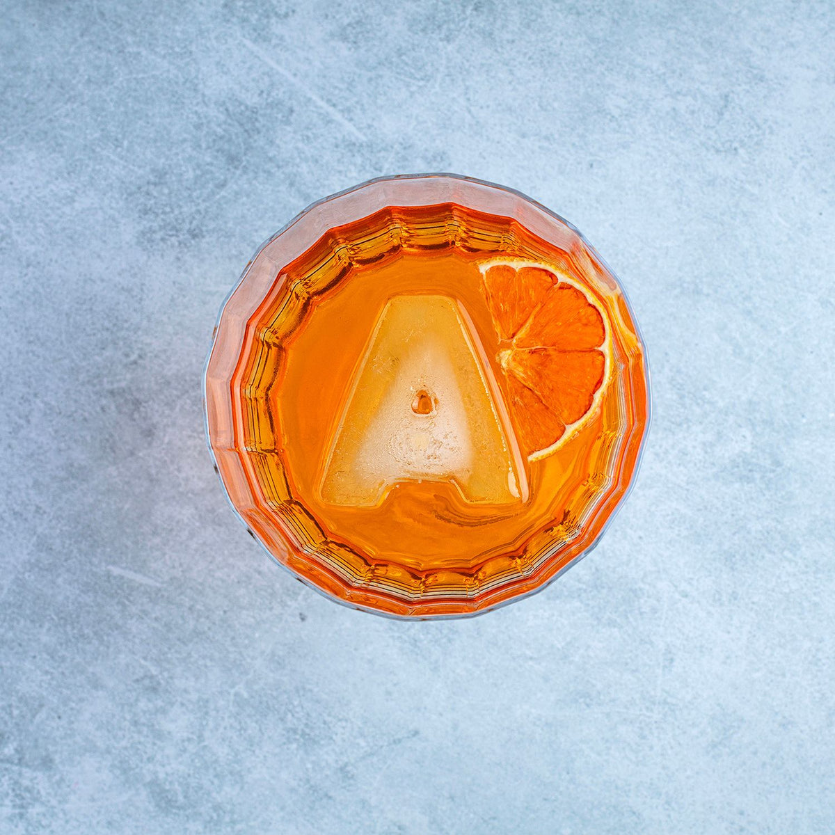 Cocktail in a glass with an orange slice on a textured gray surface