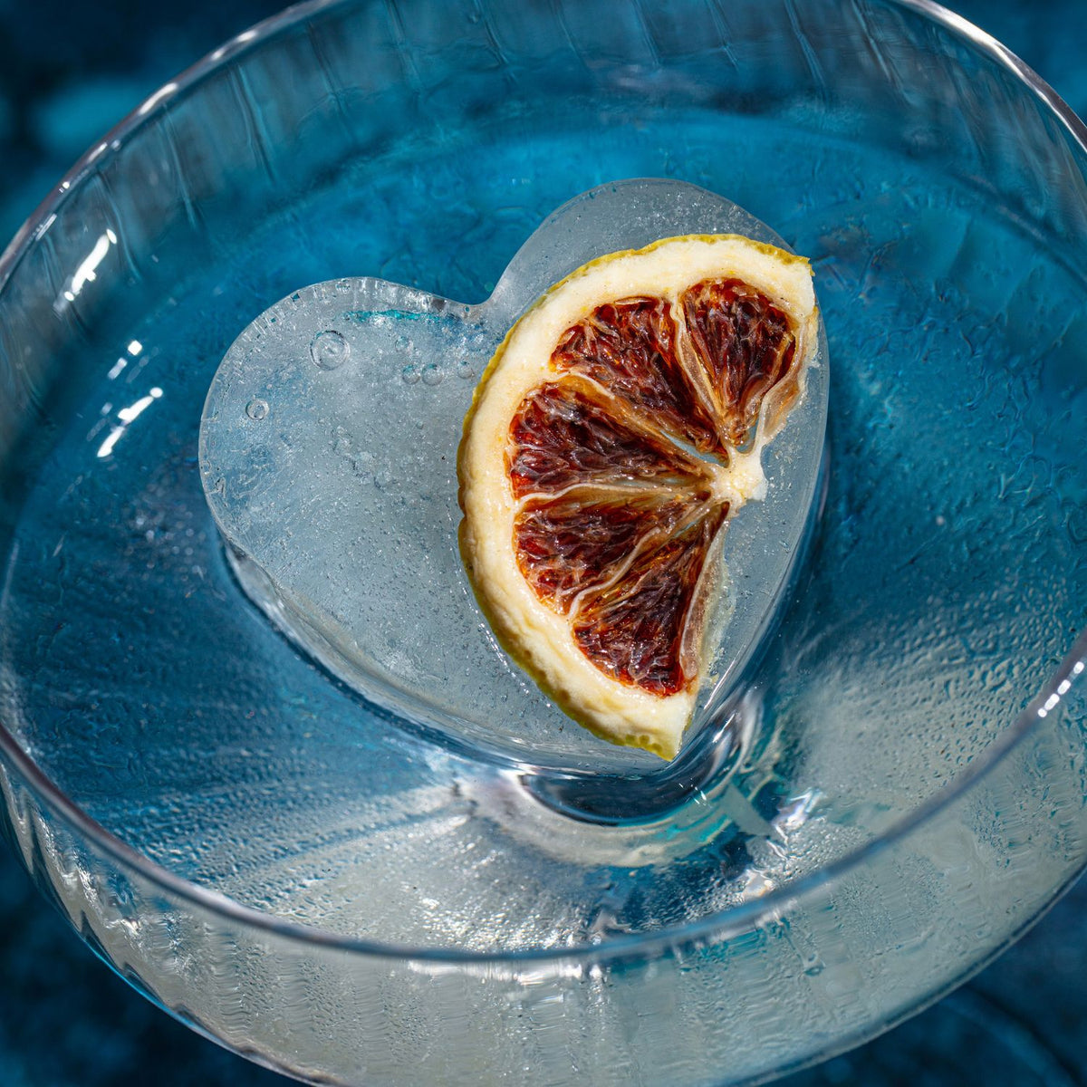 Frosted glass with a heart-shaped ice cube and a dried lemon slice inside