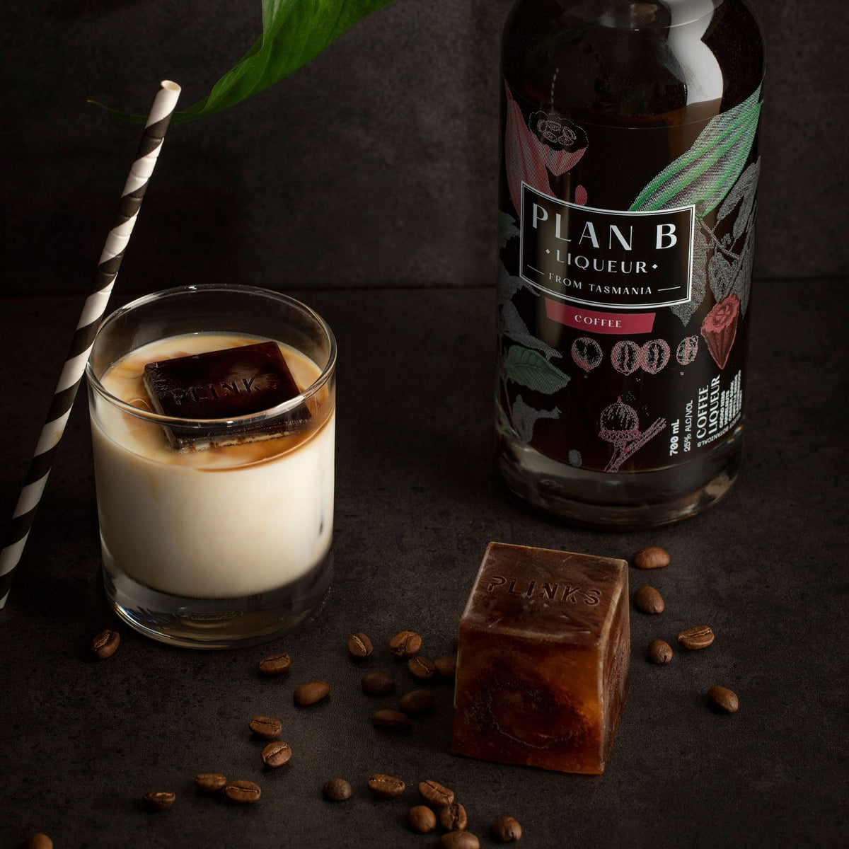 Bottle of Plan B Liqueur with a glass of coffee liqueur and coffee beans on a dark surface