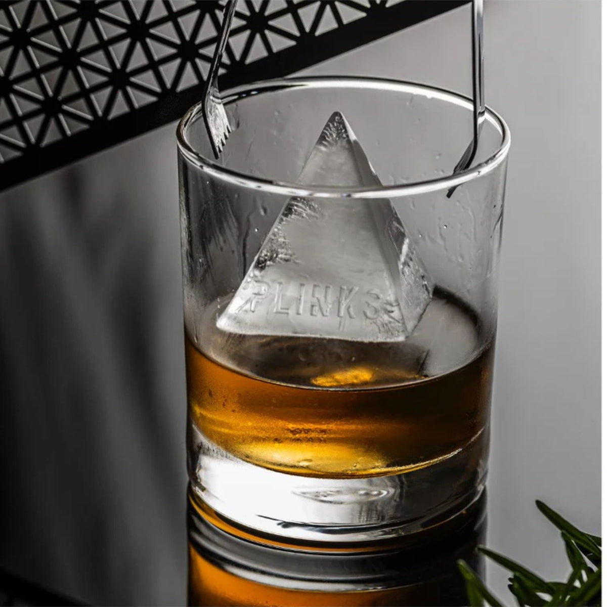 Clear glass with a triangular ice cube and amber liquid, branded &#39;FLINKS&#39;.