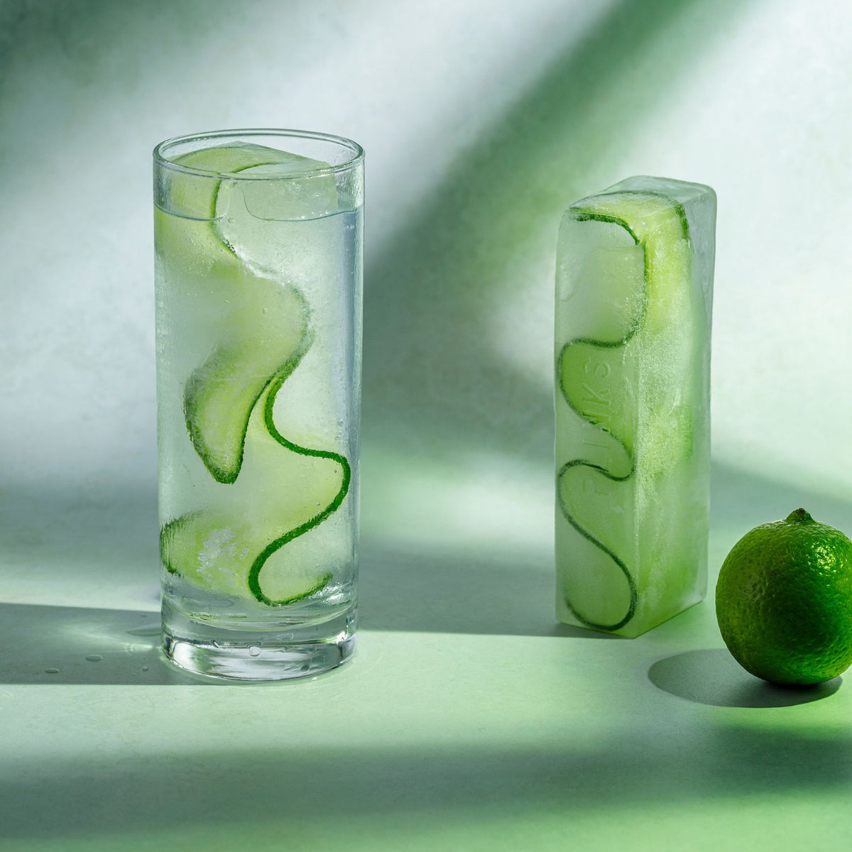 Two glasses with cucumber slices in water on a light background