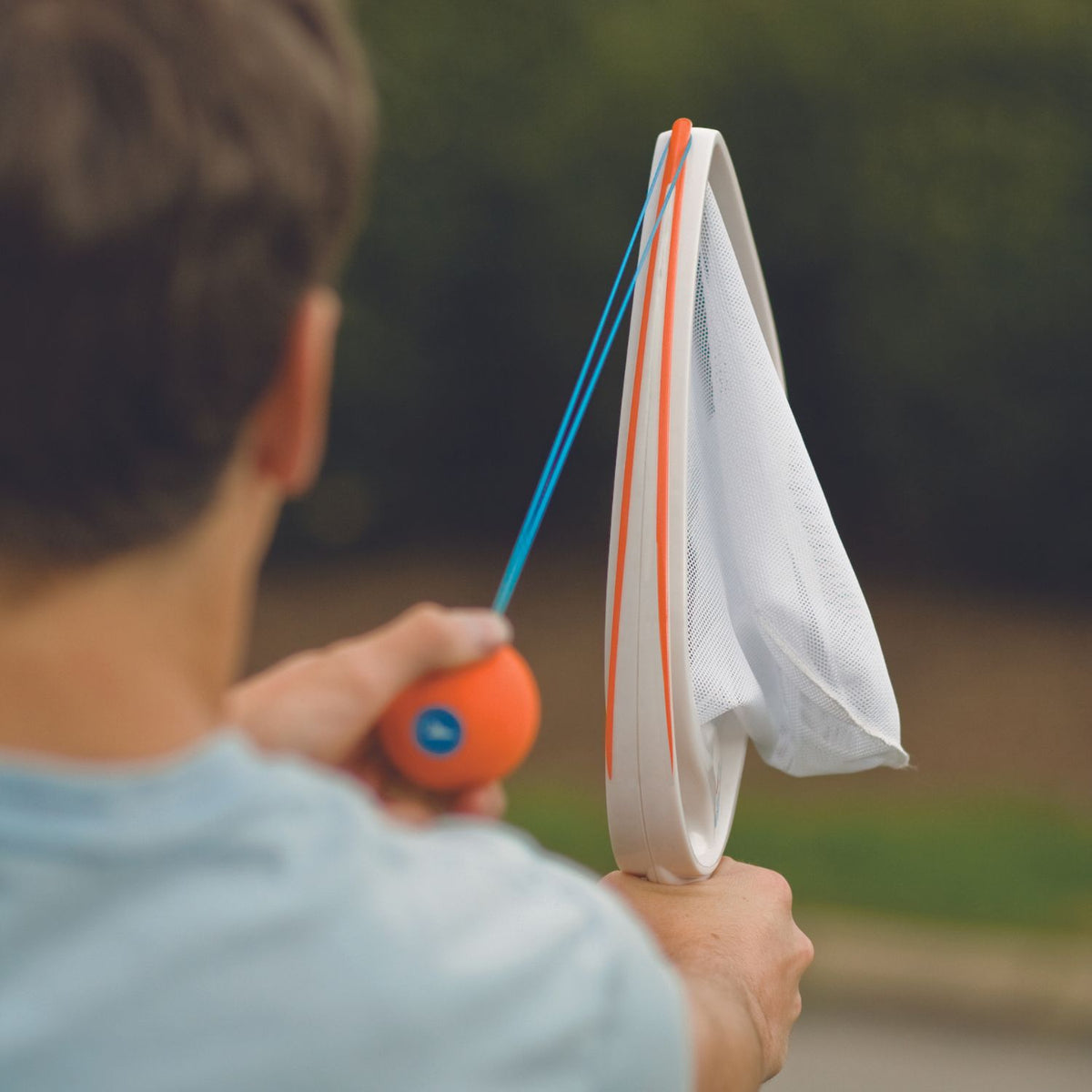 Person holding a SlingBall outdoors.