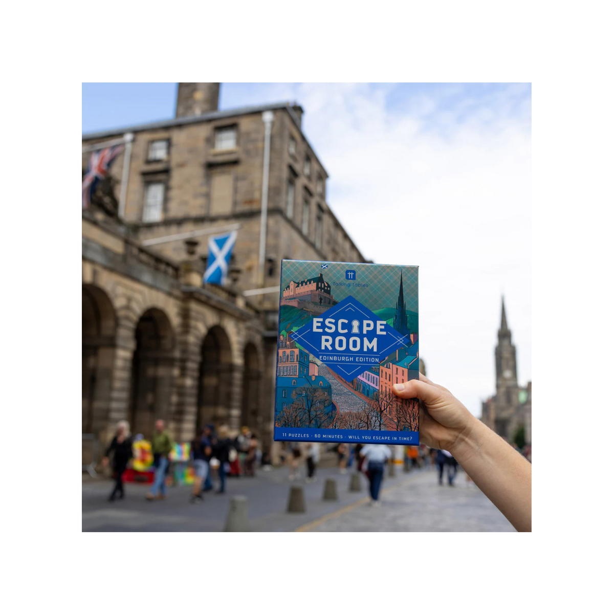 Hand holding an &#39;Escape Room&#39; book with a cityscape background