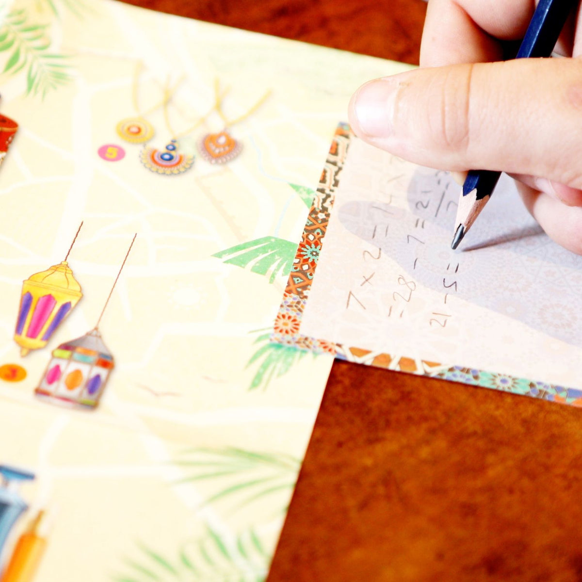 Hand holding a pencil over a piece of paper with mathematical equations on a colorful background