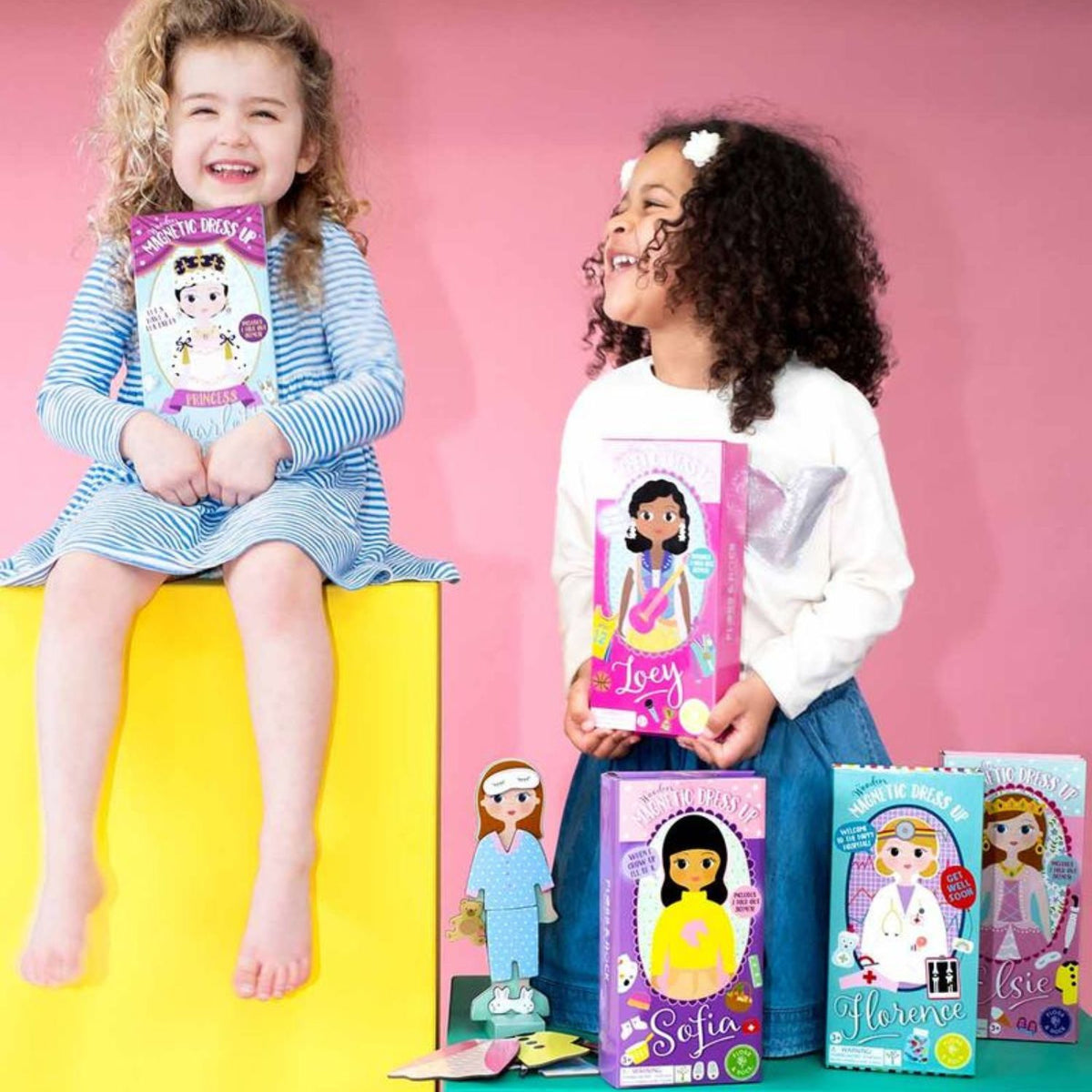Children holding magnetic dress up dolls