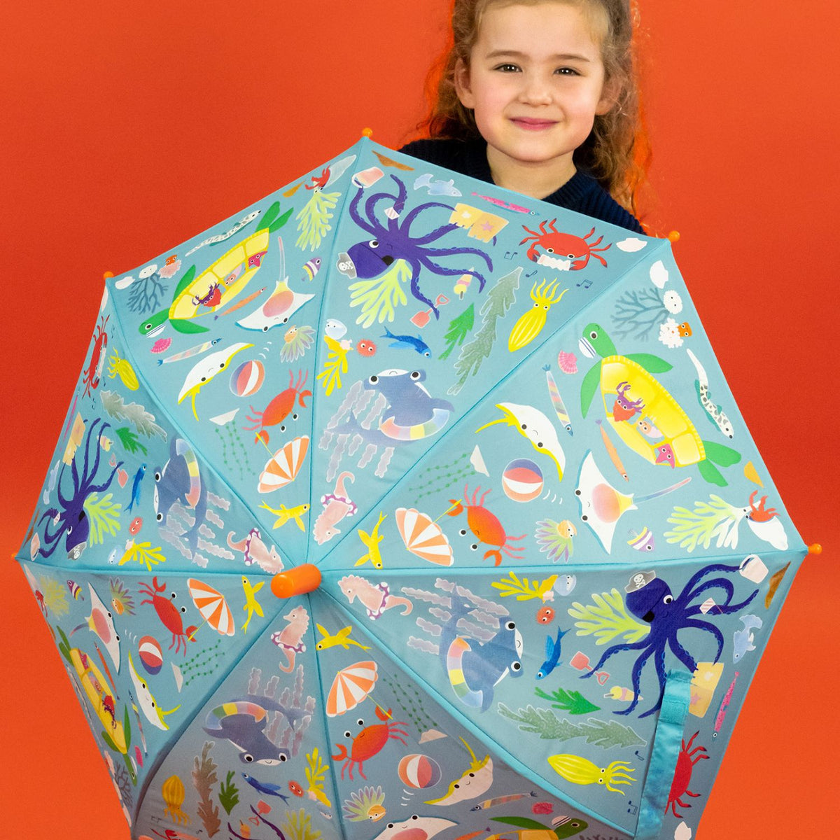 Child holding a colorful umbrella with sea creature design 