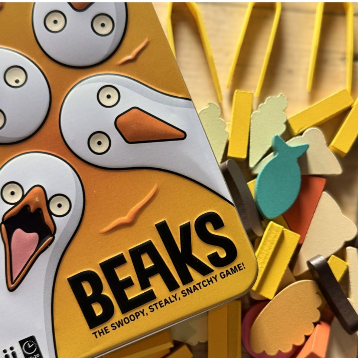 Board game tin for 'Beaks' with colorful bird illustrations and wooden pieces.
