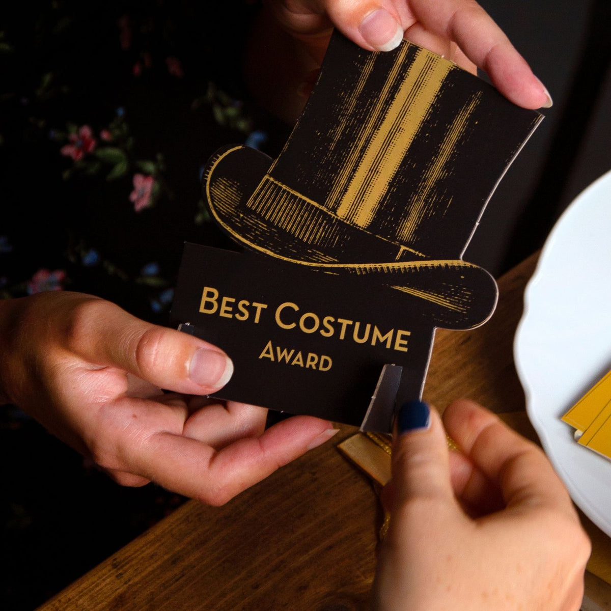 Person holding a &#39;Best Costume Award&#39; card with a top hat design.