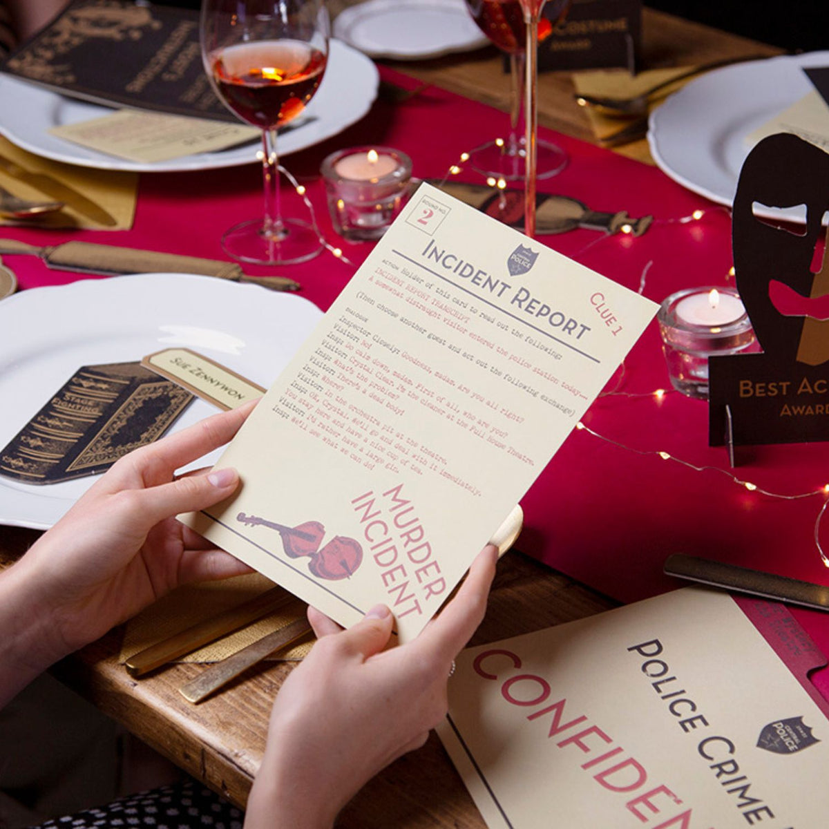 Person holding a &#39;Murder Incident&#39; incident report card at a table with wine glasses and decor.