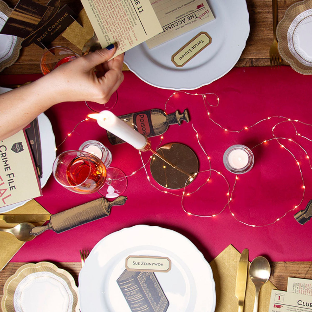 Dining table setup with red placemat, candles, and decorative items on a wooden surface.