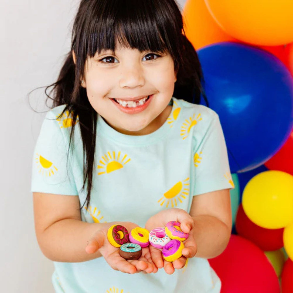 Child holding colorful donut vanilla scented erasers