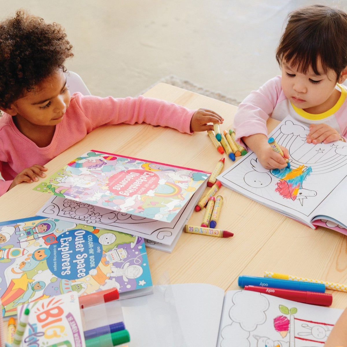 Two children sitting together with the book open to different pages, illustrating how the large format allows for shared art time.