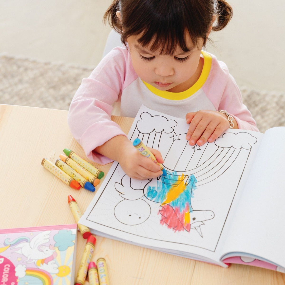 A close-up of a child’s hand using a bright crayon on the spacious 8x10 page, demonstrating the accessible design for early learners.