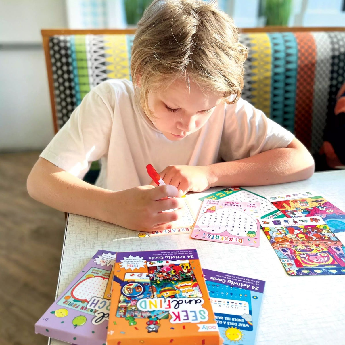 A close-up of a child’s hand circling a word on a card, demonstrating deep engagement with spelling and vocabulary building.