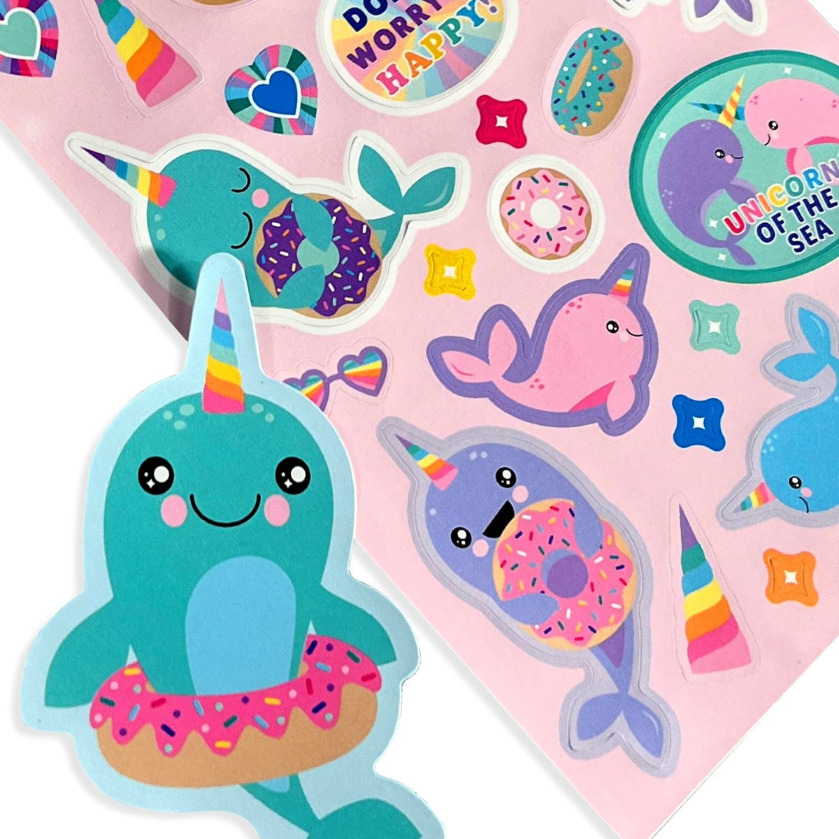 Colorful stickers with cartoon narwhals and donut-themed designs on a pink background