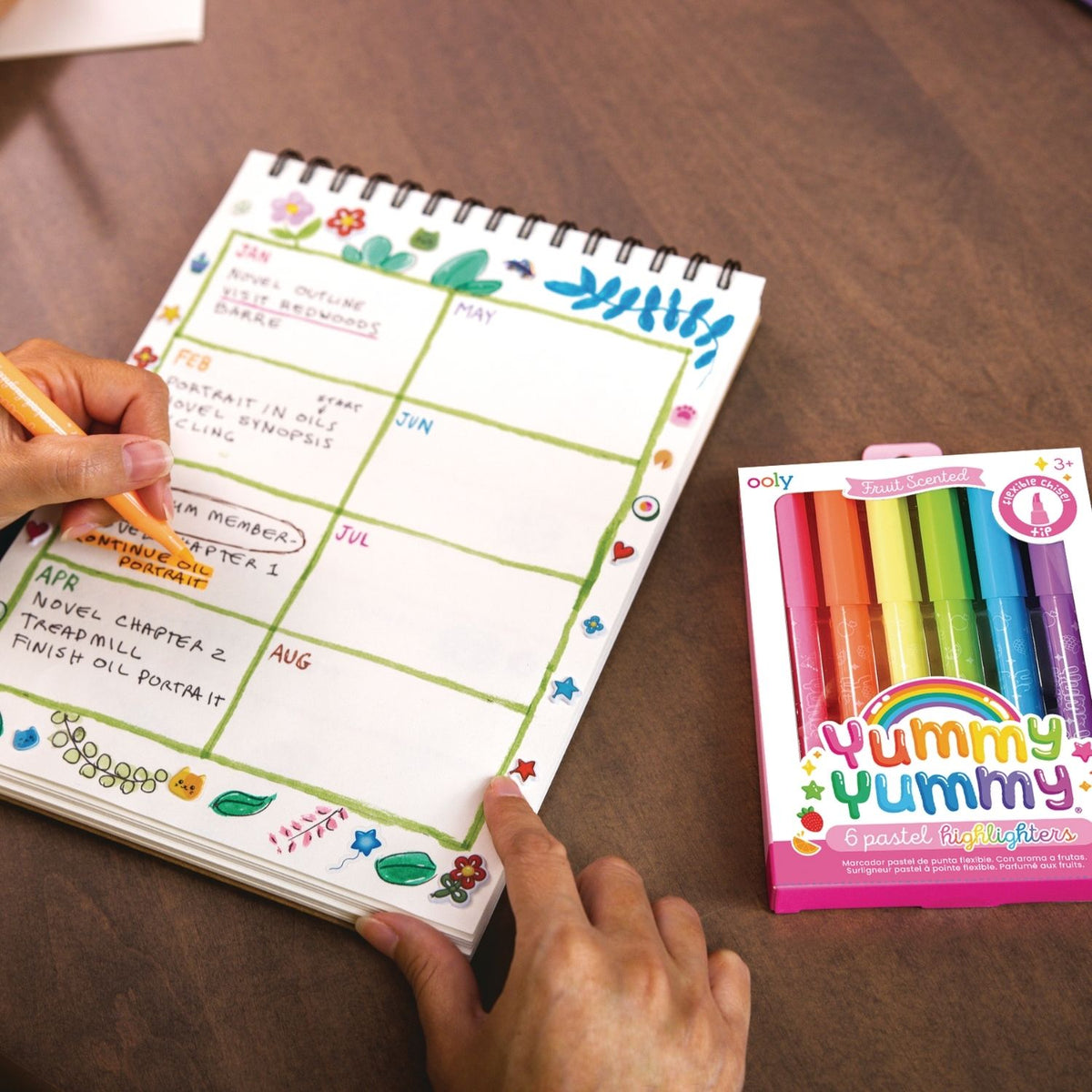 The pastel highlighters styled on a clean white desk next to a professional leather planner and a coffee cup.