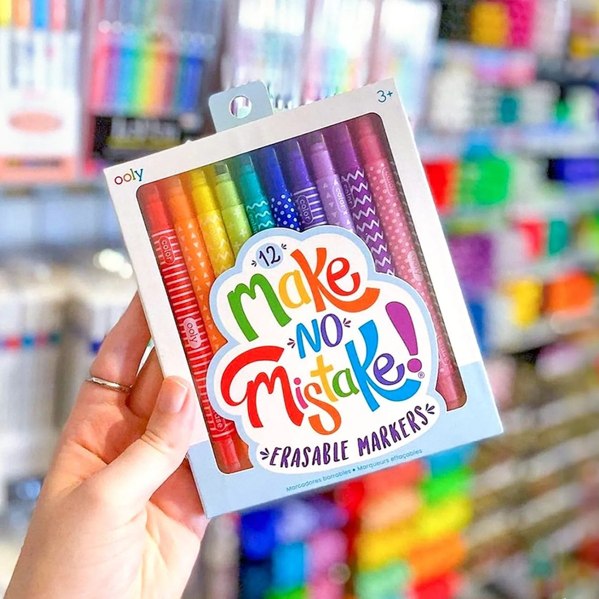 Pack of Ooly erasable markers held in front of a colorful store background