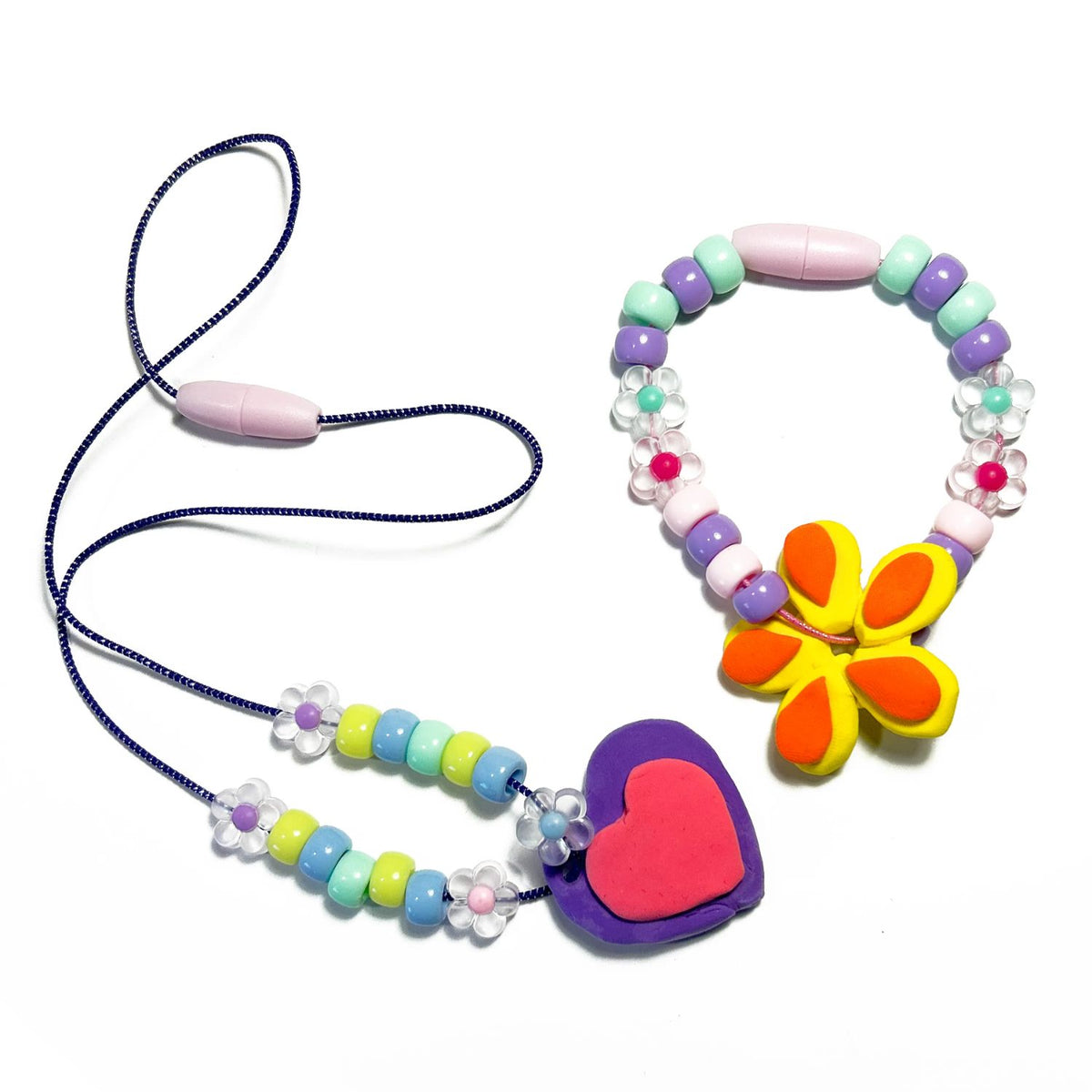 Colourful beaded and clay necklace and bracelet with a heart and flower pendant on a white background