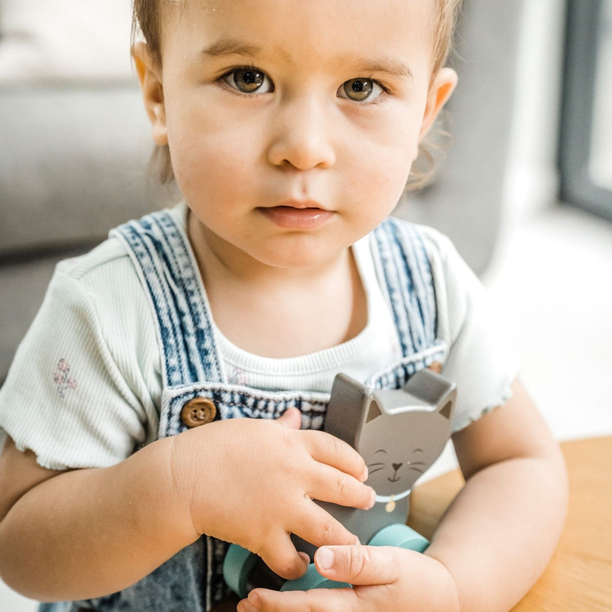 Child holding a wooden toy with a cat design 