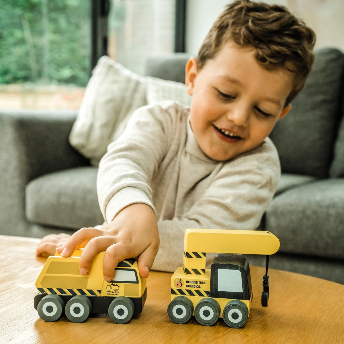 Child playing with quality wooden toy construction vehicles on a wooden play table