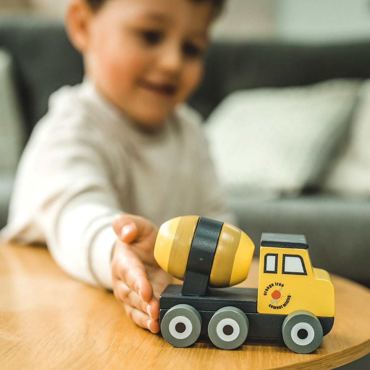 close-up shot of a toddler’s hand turning the smooth wooden mixer barrel on a playroom floor, capturing fine motor control and tactile play.
