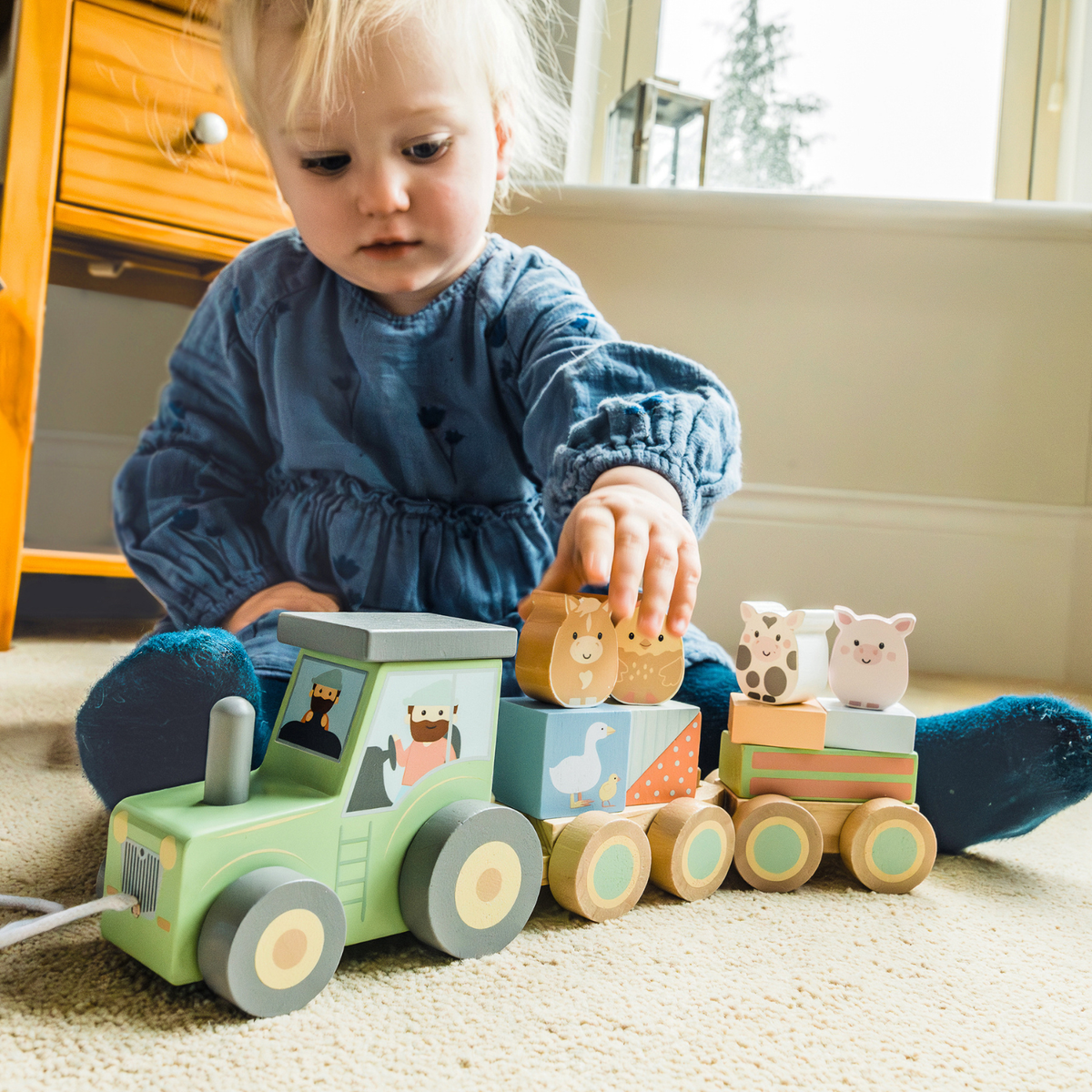 A close-up shot of a young child’s hands carefully slotting painted wooden blocks illustrating fine motor control and concentration.