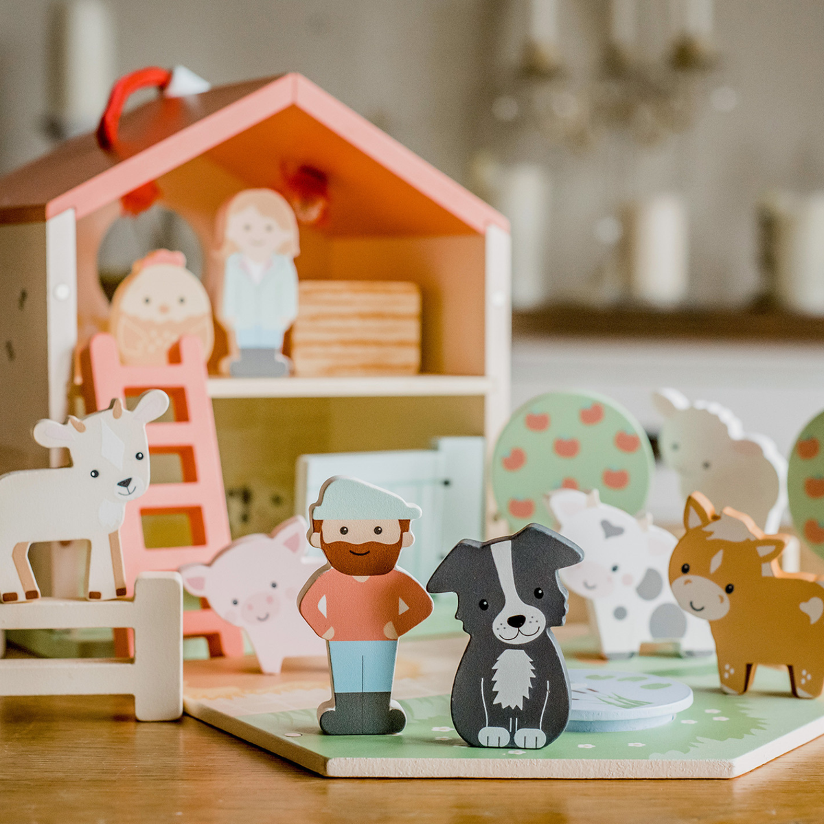 Wooden toy figures of a farmer, dog, and other animals on a wooden base with a toy house.