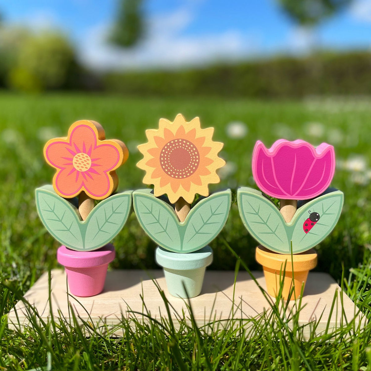 The colorful wooden flower pot stacking set arranged neatly on a grassy outdoor setting.