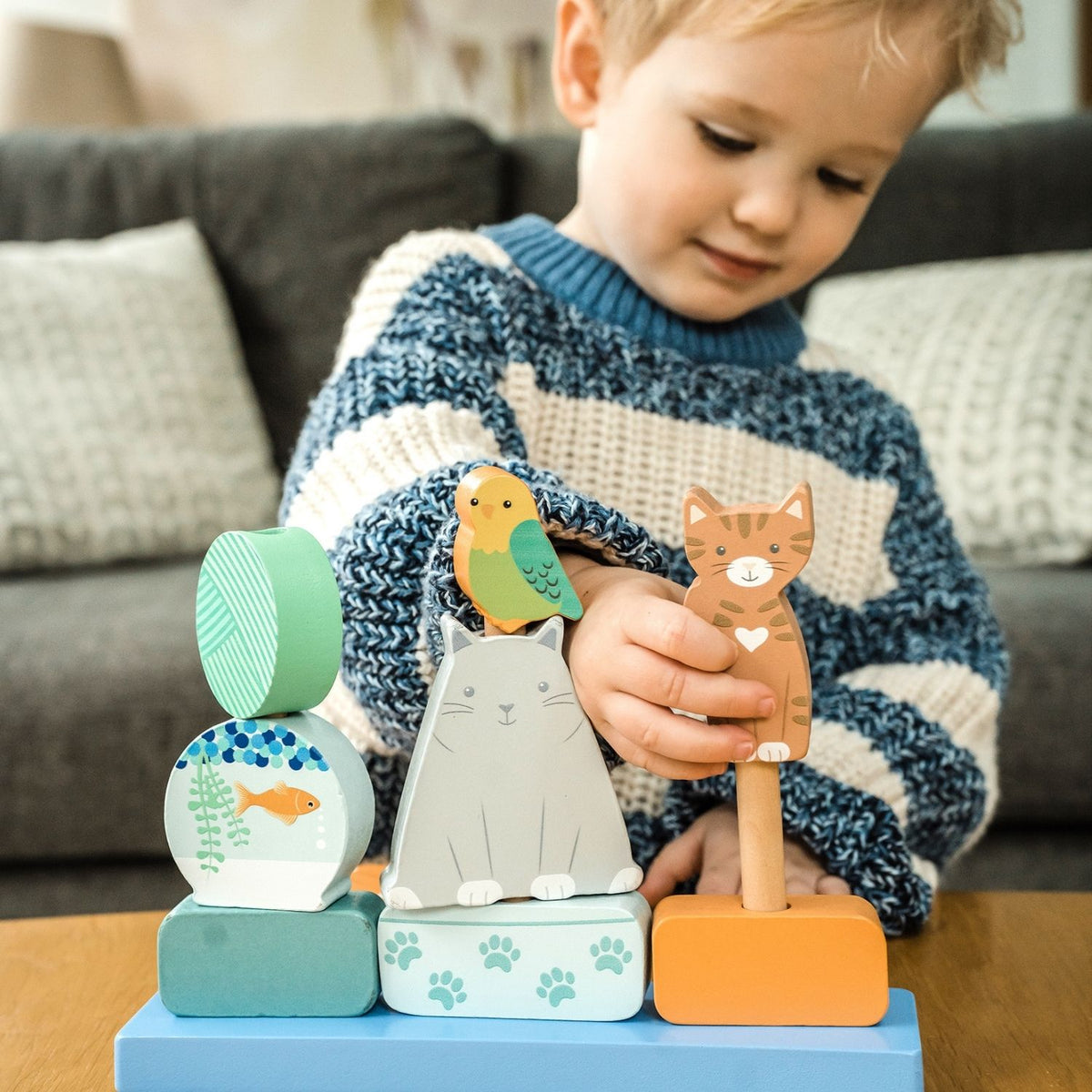 A young child happily swapping different wooden cat blocks around to create a custom kitty tower.