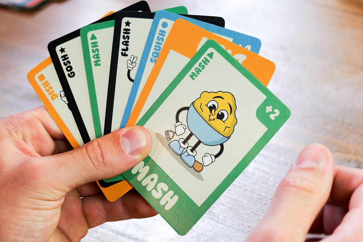 Hand holding a set of playing cards with cartoon character design on a blurred background