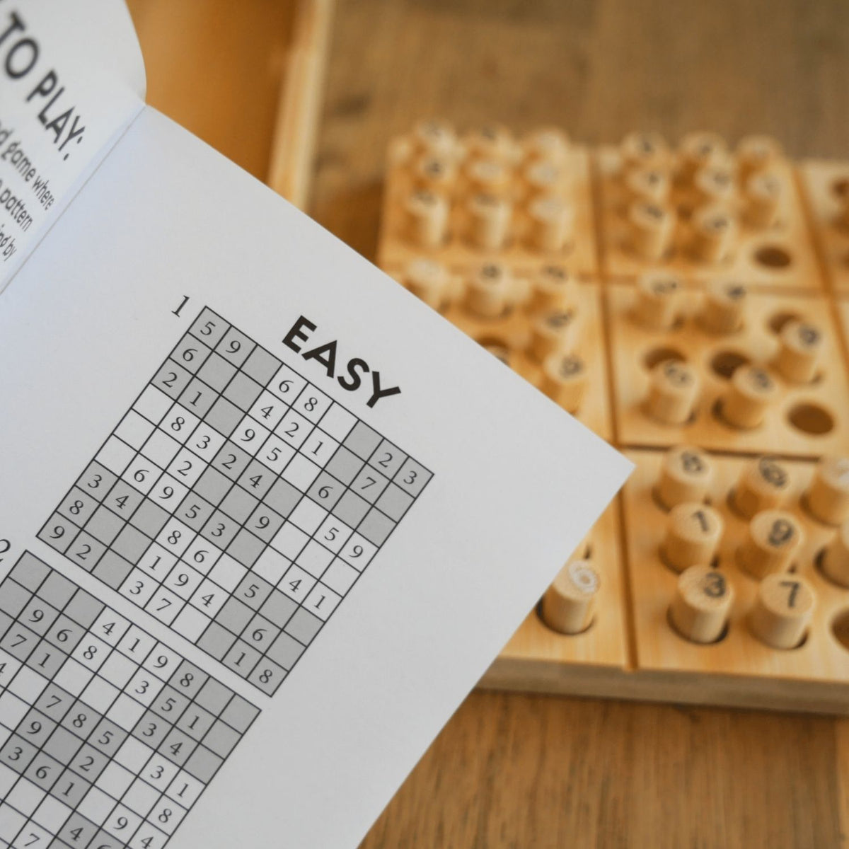 Sudoku puzzle with wooden pegs and instruction sheet on a wooden surface