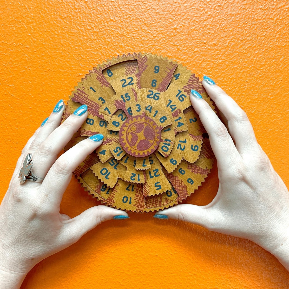 A person’s hands turning the wooden dials of the Grecian Computer, attempting to align the number columns to reach the sum of 42.