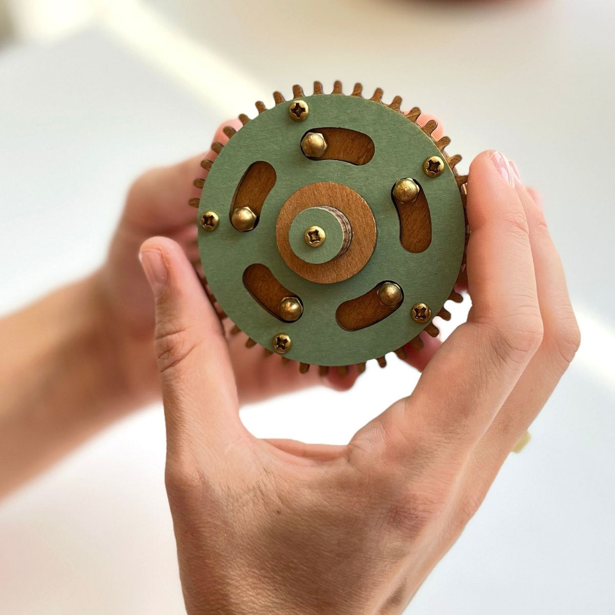 A close-up of a person using a magnetic pin to disengage the internal locking mechanism of the level four difficulty gear puzzle.