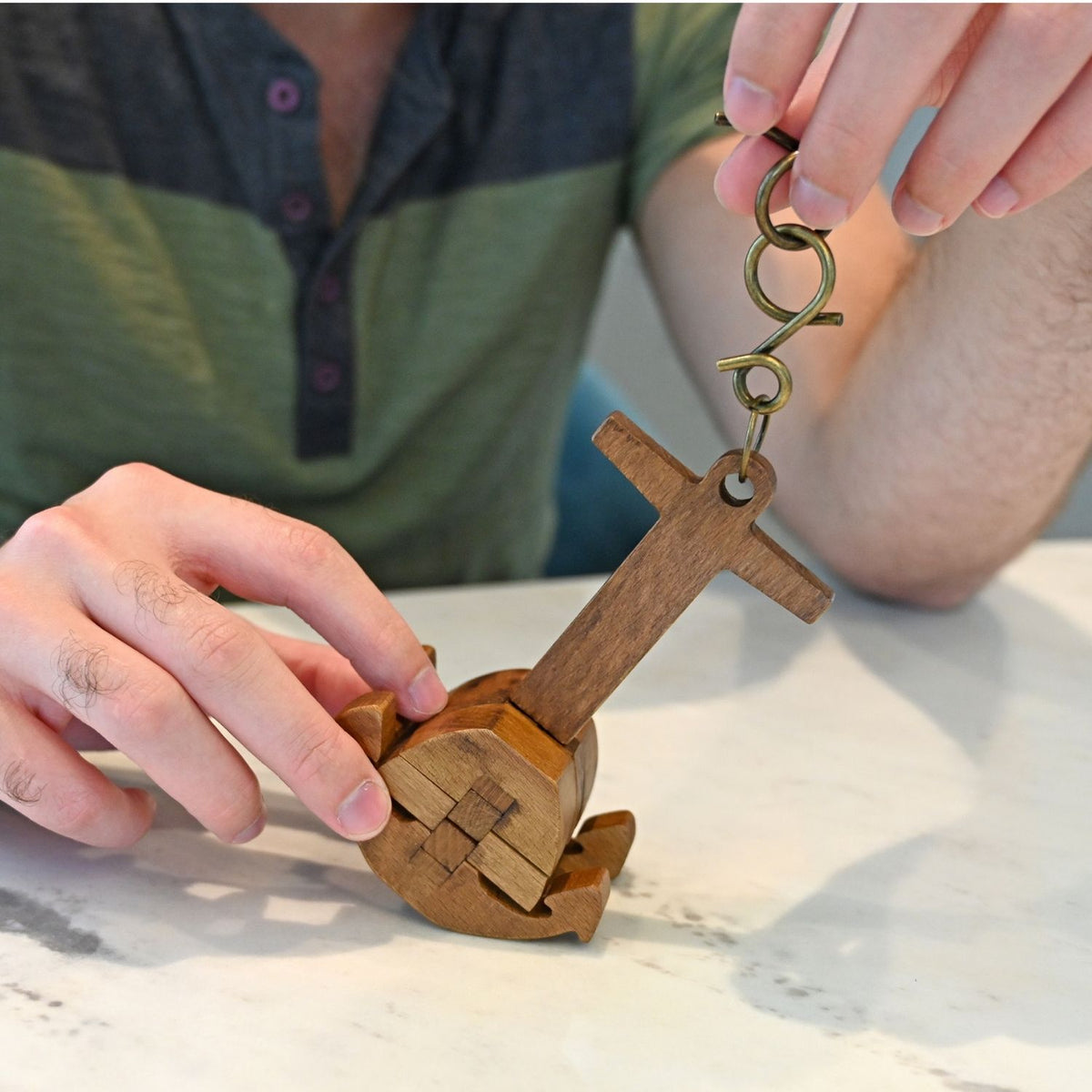 Wooden puzzle keychain being assembled by a person on a marble surface