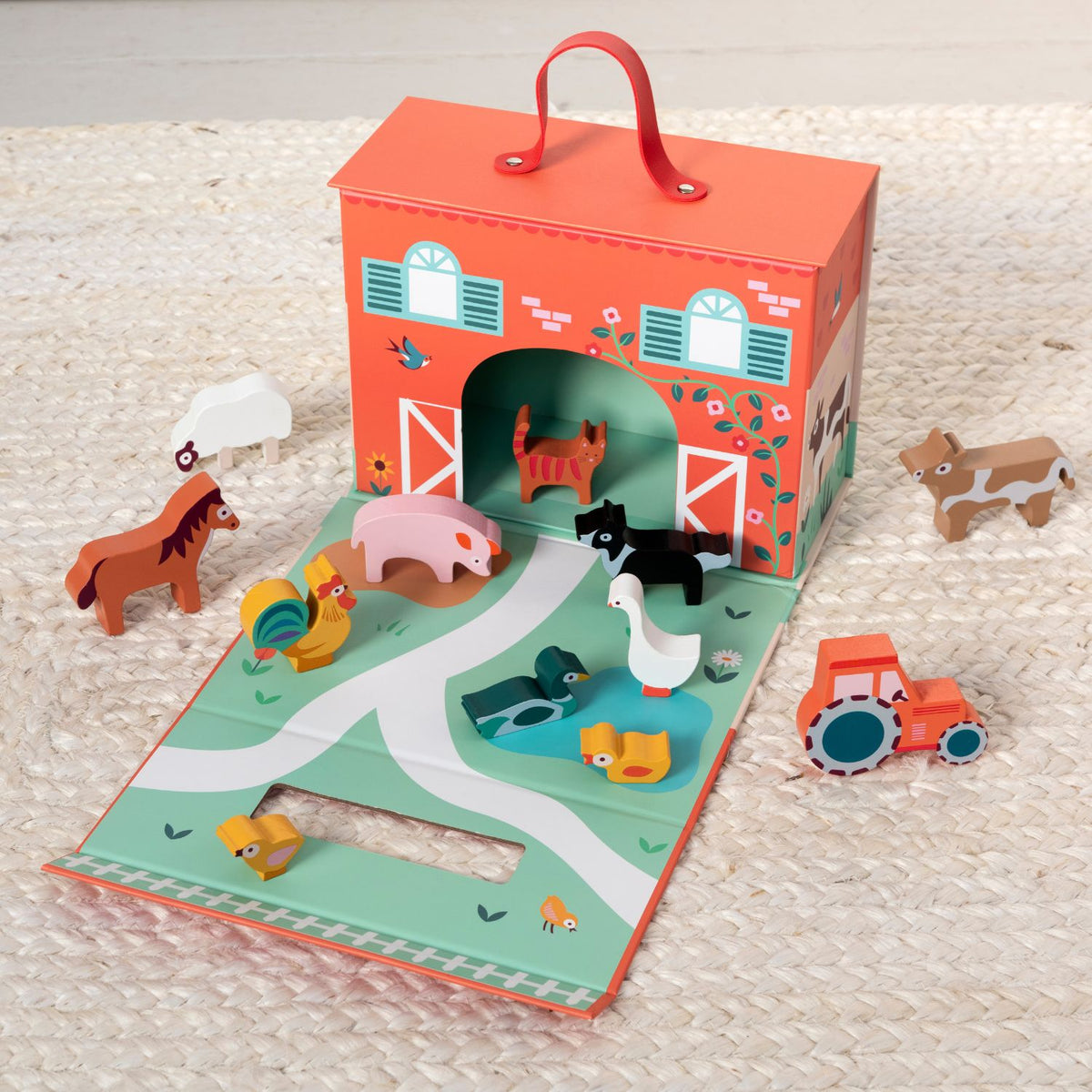 Children&#39;s toy set with a barn-shaped book and farm animal figures on a textured surface.