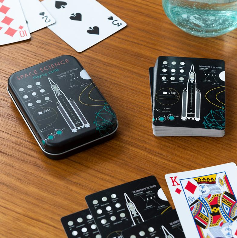 Space-themed playing cards with rocket designs on a wooden table.